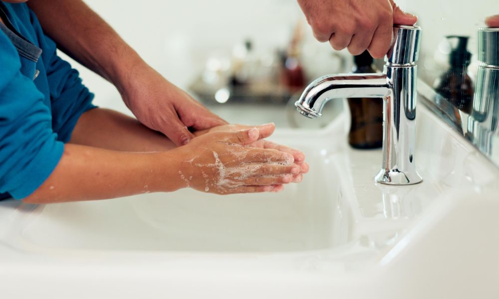Child washing hand with their parent