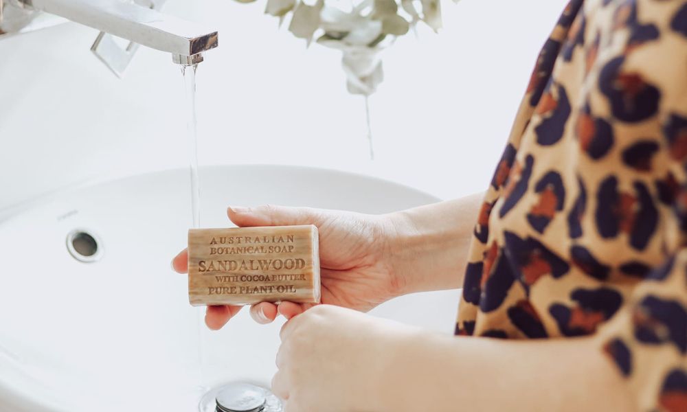 Sandalwood with cocoa butter soap bar lifestyle shot. using soap to moisturise 