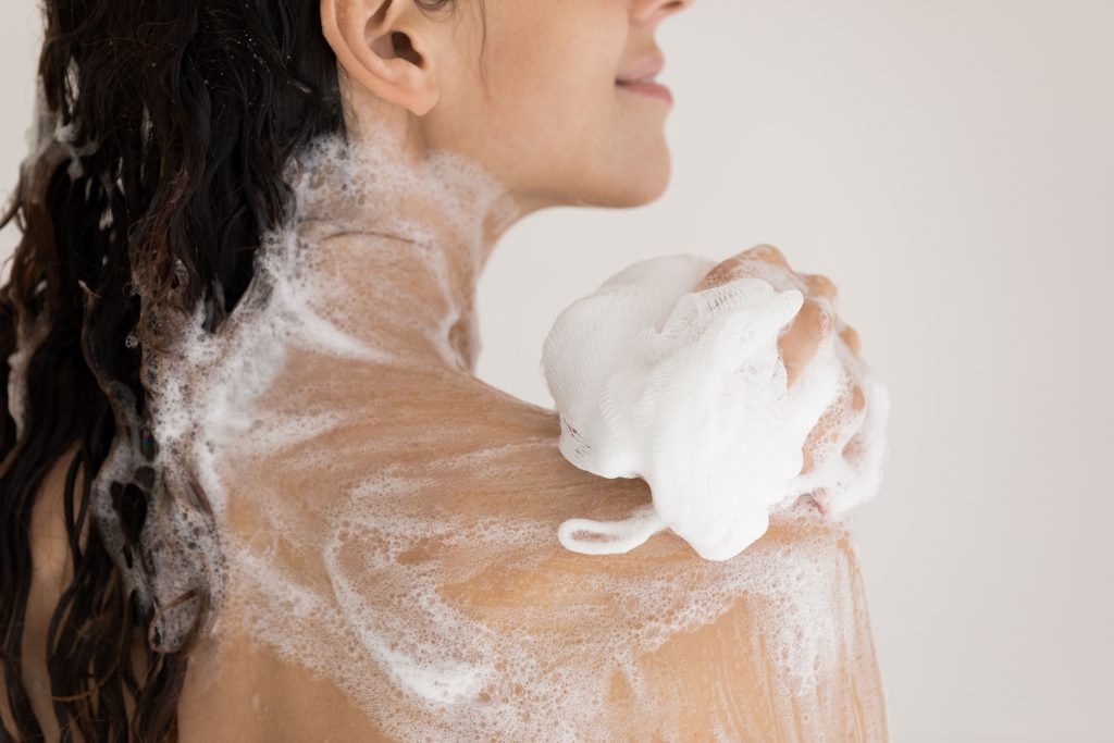 soapy lady washing herself with shower puff
